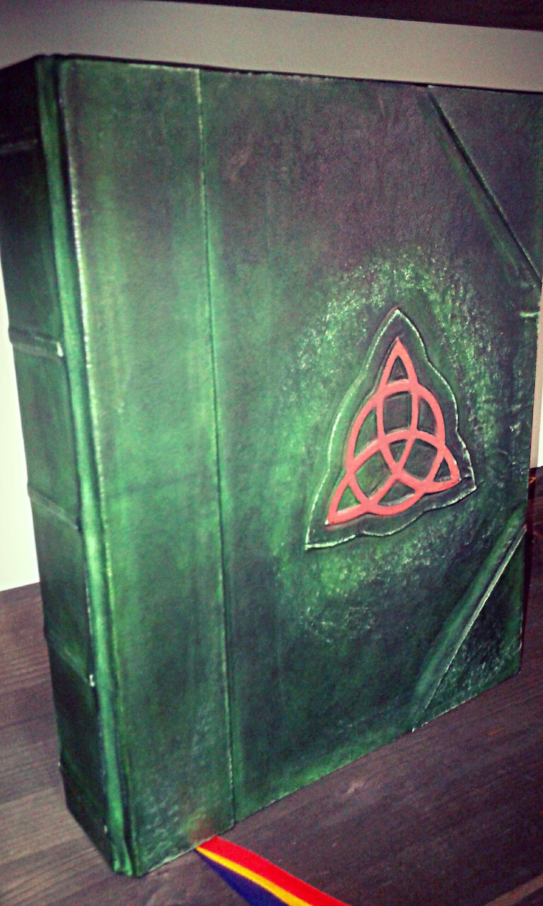 May include: A green leather-bound book with a red, three-pointed star symbol on the front cover.