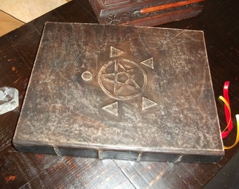 May include: A dark brown leather-bound journal with a five-pointed star and other symbols embossed on the cover. The journal has two red and yellow ribbon bookmarks.