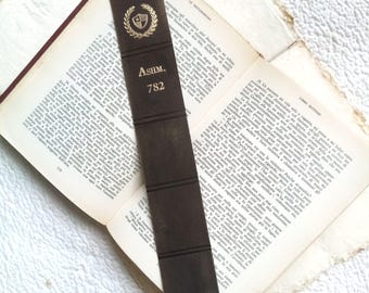 May include: A brown leather bookmark with gold lettering that reads "ASHM. 782". The bookmark has a gold crest with a wreath and a shield.