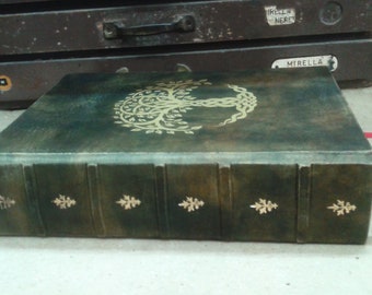 May include: A dark green leather-bound book with gold accents. The cover features a gold tree of life design with intricate details. The book has five raised bands and gold leaf accents on the spine.