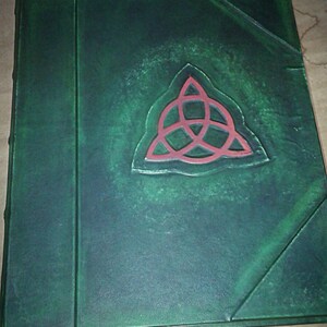 May include: A green leather-bound journal with a red, three-pointed star embossed on the front cover.