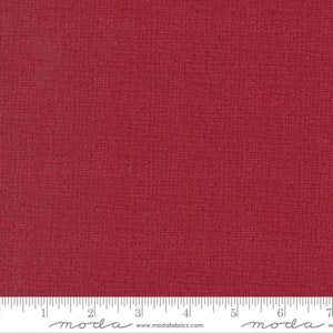 May include: A close-up of a solid red fabric with a subtle textured pattern. The fabric is measured with a ruler in inches.