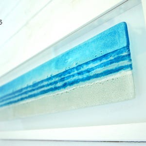 panoramic 3D fused glass blue beach scene wall art in a white wooden frame with cord across the back, ready to hang 60x20cm with cable across the back, handmade by glass artis Matt Adkins in Dorset, UK