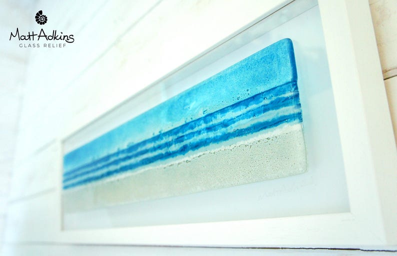 panoramic 3D fused glass blue beach scene wall art in a white wooden frame with cord across the back, ready to hang 60x20cm with cable across the back, handmade by glass artis Matt Adkins in Dorset, UK