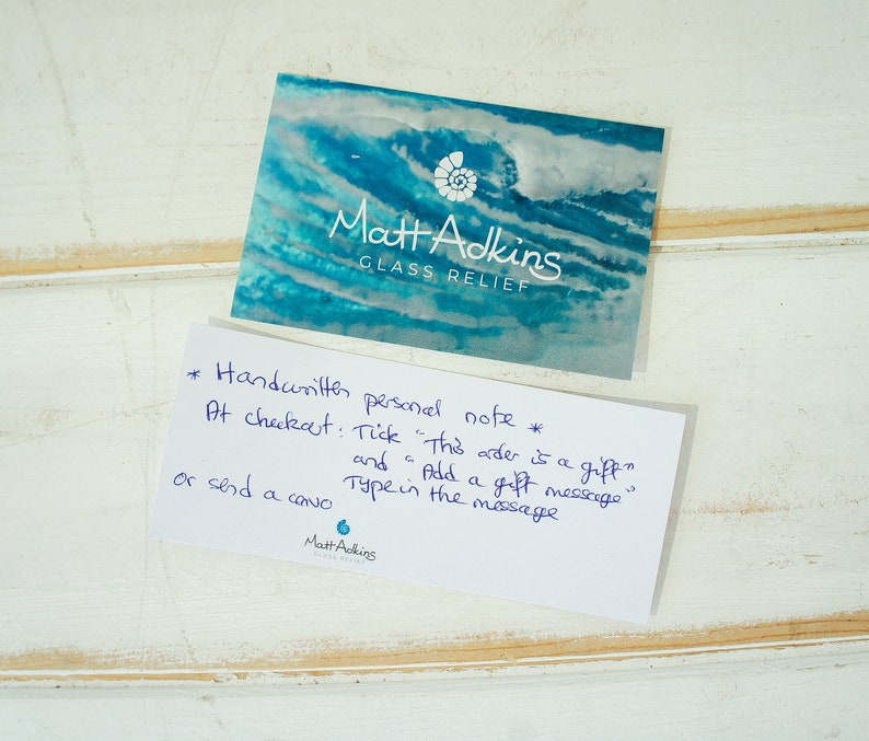 May include: A white card with handwritten instructions for adding a personal note to an order at checkout. The text reads: "*Handwritten personal note* At checkout: Tick "This order is a gift" and Add a gift message or send a card Type in the message"  The card also includes the name "Matt Adkins" and the words "Glass Relief".