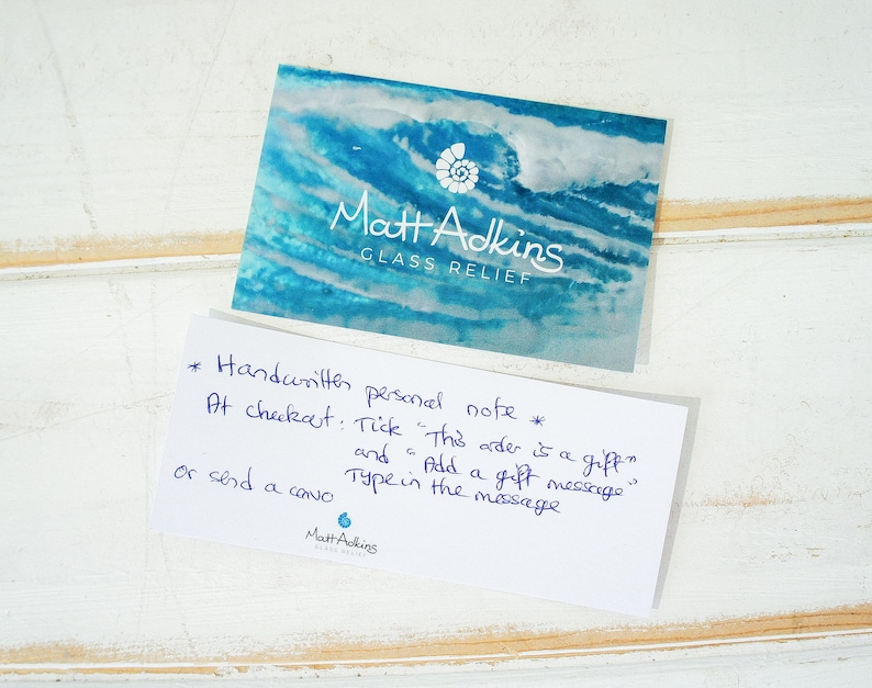 May include: A rectangular business card with a blue and white abstract wave pattern, a white shell icon, and the text Matt Adkins GLASS RELIEF. Below it, a white card with blue handwritten text explaining how to add a gift message at checkout.