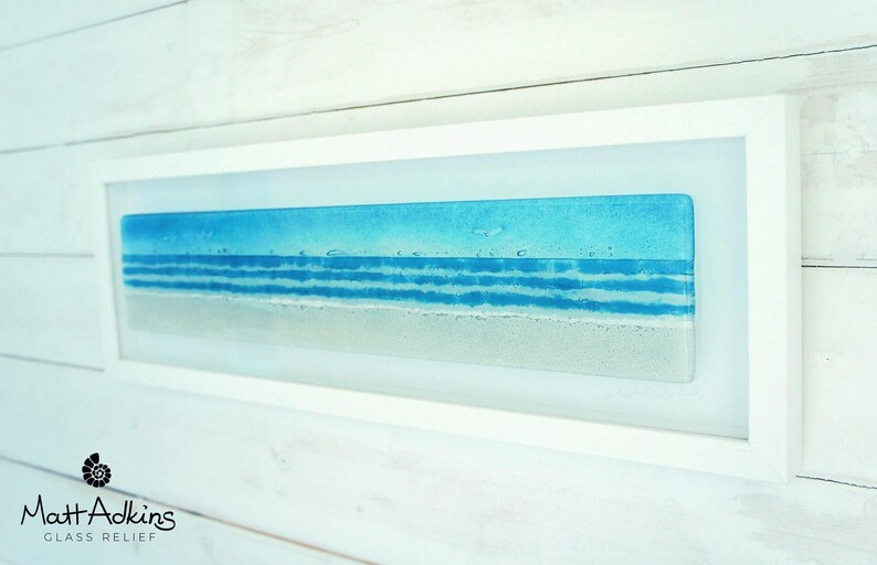panoramic 3D fused glass blue beach scene wall art in a white wooden frame with cord across the back, ready to hang 60x20cm with cable across the back, handmade by glass artis Matt Adkins in Dorset, UK