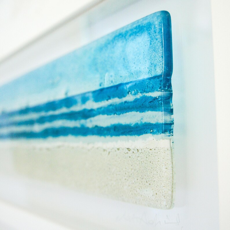 panoramic 3D fused glass blue beach scene wall art in a white wooden frame with cord across the back, ready to hang 60x20cm with cable across the back, handmade by glass artis Matt Adkins in Dorset, UK