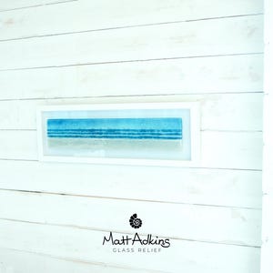 panoramic 3D fused glass blue beach scene wall art in a white wooden frame with cord across the back, ready to hang 60x20cm with cable across the back, handmade by glass artis Matt Adkins in Dorset, UK