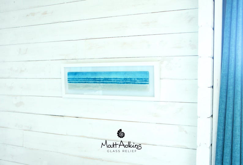 panoramic 3D fused glass blue beach scene wall art in a white wooden frame with cord across the back, ready to hang 60x20cm with cable across the back, handmade by glass artis Matt Adkins in Dorset, UK