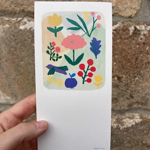 Peut inclure: Une carte blanche avec une illustration florale colorée. Le dessin comprend une fleur rose, des baies rouges, un oiseau violet et une pomme bleue. Le nom de l'artiste, Matilda Grew, est imprimé en bas.