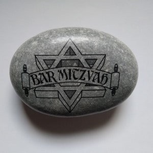 May include: A gray stone with a black Star of David and the words "Bar Mitzvah" inscribed on it.