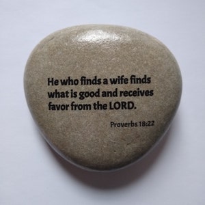 May include: A gray stone with the text "He who finds a wife finds what is good and receives favor from the LORD. Proverbs 18:22" engraved on it.