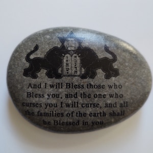 May include: A gray stone with a black inscription that reads "And I will Bless those who Bless you, and the one who curses you I will curse, and all the families of the earth shall be Blessed in you."