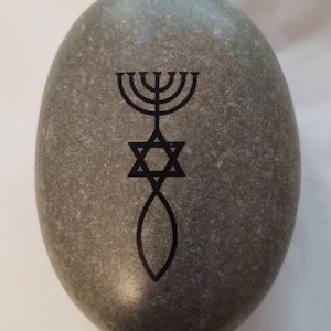 May include: A gray stone with a black menorah, Star of David, and a fish symbol engraved on it.