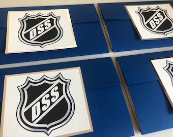 May include: Four blue envelopes with white inserts featuring a black and silver hockey logo with the letters "DSS" inside. The envelopes are folded in half and have a gold trim.