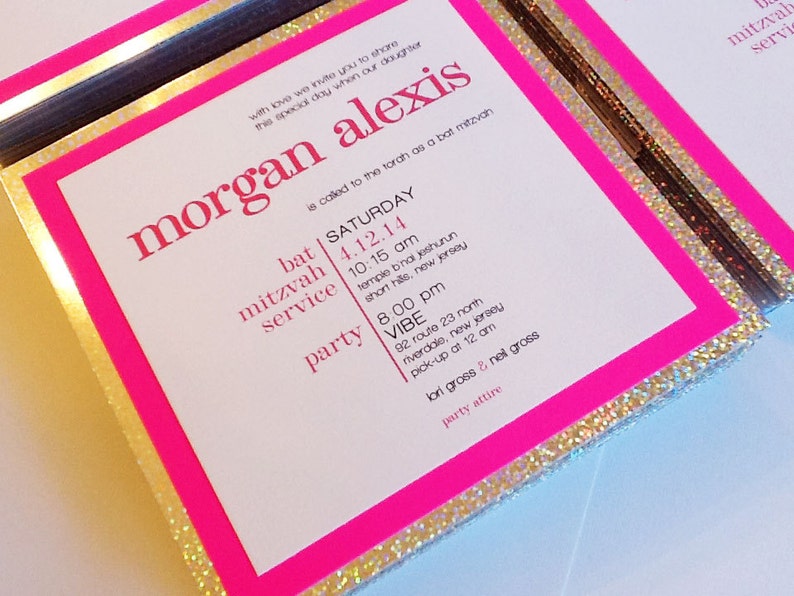 May include: Pink and gold glitter bat mitzvah invitation with the text "morgan alexis" in large, bold, pink letters. The invitation includes the date and time of the bat mitzvah service and party, as well as the location of both events.