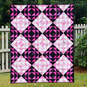Könnte beinhalten: Eine rosa und schwarze Steppdecke mit geometrischem Muster. Die Steppdecke besteht aus Dreiecken und Quadraten und hat ein modernes Design.