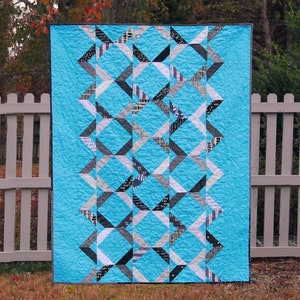 May include: A blue and white quilt with a geometric pattern. The quilt is made up of triangles and squares, and it has a modern, abstract design.
