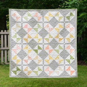 May include: A grey, white, pink, yellow and green patchwork quilt with a diamond pattern. The quilt is made of various fabrics with floral and geometric designs.