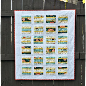 K&ouml;nnte beinhalten: Eine wei&szlig;e Steppdecke mit rotem Rand. Die Steppdecke besteht aus 18 Quadraten, jedes mit einem anderen Blumenmuster. Die Quadrate sind in einem Gittermuster angeordnet.