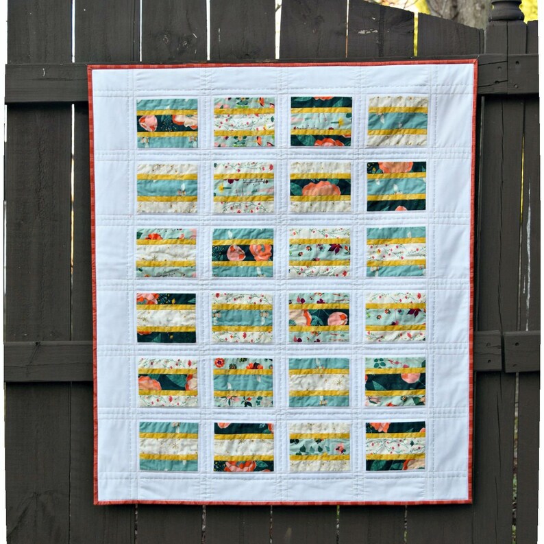 K&ouml;nnte beinhalten: Eine wei&szlig;e Steppdecke mit rotem Rand. Die Steppdecke besteht aus 18 Quadraten, jedes mit einem anderen Blumenmuster. Die Quadrate sind in einem Gittermuster angeordnet.