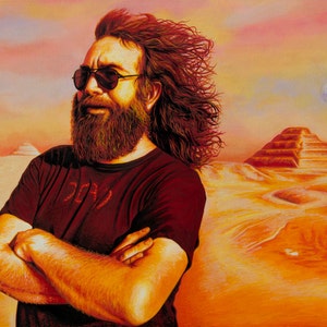 May include: A man with long, red hair and a beard is wearing sunglasses and a red t-shirt with a graphic design. He is standing in a desert landscape with a pyramid in the background. The sky is a vibrant orange and pink.