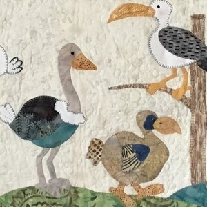 Puede incluir: Un edred&oacute;n de tela con p&aacute;jaros aplicados. Los p&aacute;jaros incluyen un avestruz, una gaviota posada en una rama y un dodo. Los p&aacute;jaros son en tonos de gris, marr&oacute;n, azul y blanco, sobre un fondo color crema.
