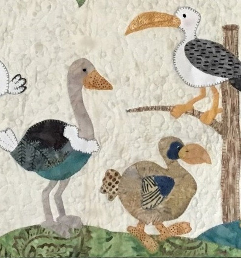 Puede incluir: Un edred&oacute;n de tela con p&aacute;jaros aplicados. Los p&aacute;jaros incluyen un avestruz, una gaviota posada en una rama y un dodo. Los p&aacute;jaros son en tonos de gris, marr&oacute;n, azul y blanco, sobre un fondo color crema.