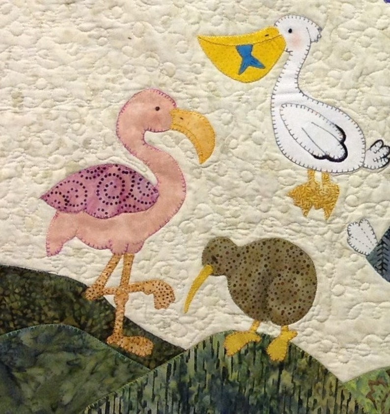 Puede incluir: Un edred&oacute;n textil con dise&ntilde;os de aves aplicados. Un flamenco rosa con pico amarillo y ala estampada se encuentra cerca de un kiwi marr&oacute;n con un pico largo amarillo. Tambi&eacute;n se presenta un pel&iacute;cano blanco con bolsa amarilla y pez azul.