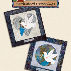 May include: Two square fabric art pieces with dove designs. One features a dove over a heart, the other over a globe. The text "Wings of a Dove" and dimensions 50.8cm x 50.8cm are at the bottom. The brand name "Harebrained Happenings" is at the top.