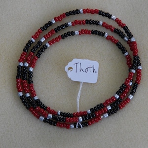 May include: A triple-strand beaded necklace with red, black, and silver beads. The necklace is labeled "Thoth".