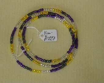 May include: A multi-strand beaded necklace with purple, yellow, and silver beads. The necklace is labeled "Non-Binary Pride".