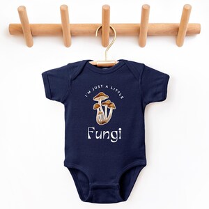 May include: A navy blue baby onesie with a white graphic of mushrooms and the text "I'm just a little Fungi".