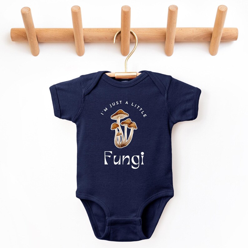 May include: A navy blue baby onesie with a white graphic of mushrooms and the text "I'm just a little Fungi".