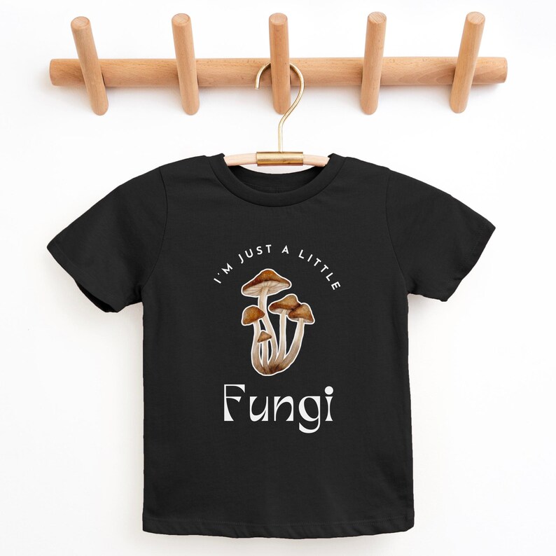 May include: Black t-shirt with a white graphic of mushrooms and the text "I'm just a little Fungi".