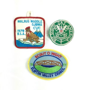 May include: Three embroidered patches. The first patch is red, white, and blue with a walrus and the text "Walrus Waddle Ojibwa CVC 1979 B.S.A.". The second patch is green with a white eagle and the text "Boy Scouts of America Be Prepared". The third patch is blue, green, and yellow with a bridge and the text "Scout O Might 1977 Clinton Valley Council".