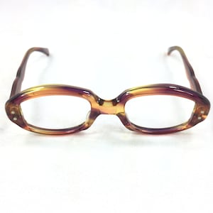 May include: A pair of tortoiseshell eyeglasses with a purple tint. The glasses have a rectangular shape with rounded edges.