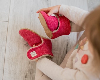 Red handmade baby booties in different sizes from little babies to adults, women cozy slippers for autumn or winter with teddy wool lining