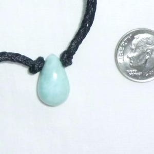K&ouml;nnte beinhalten: Ein hellblauer tropfenf&ouml;rmiger Anh&auml;nger an einer schwarzen Schnurkette. Der Anh&auml;nger ist etwa so gro&szlig; wie eine Zehn-Cent-M&uuml;nze.
