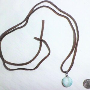 May include: A light blue and white gemstone pendant on a brown leather cord necklace.