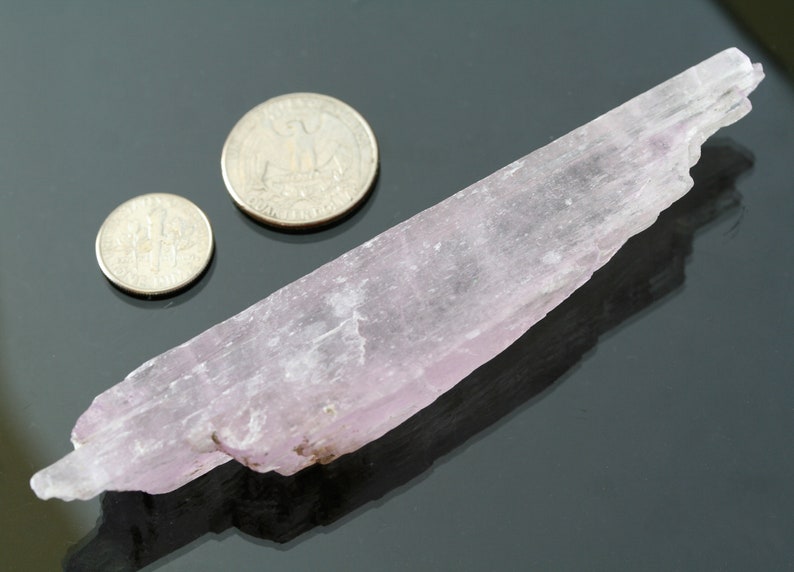 May include: A pale pink selenite crystal, about 5 inches long, next to two US quarters for scale.