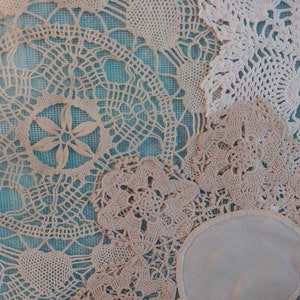 May include: A collection of white crocheted doilies with intricate patterns, arranged on a blue background.