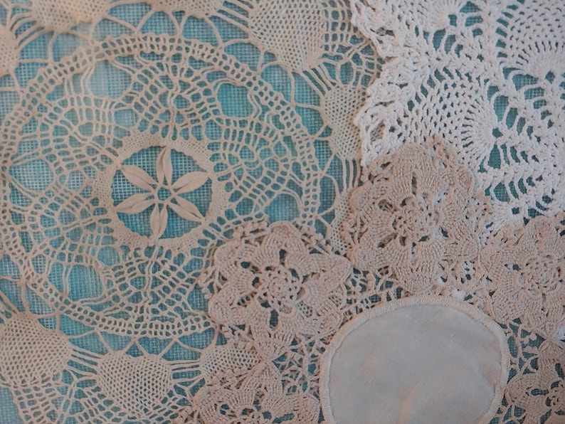 May include: A collection of white crocheted doilies with intricate patterns, arranged on a blue background.