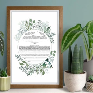 May include: A rectangular wooden frame containing a white document with a circular botanical wreath of green leaves and branches. The document features printed Hebrew and English text, including blank lines for signatures and dates at the bottom.