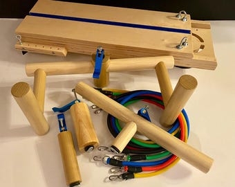 May include: A wooden Pilates reformer with various components, including wooden dowels, handles, and resistance bands in multiple colors. The reformer has a light wood finish with a blue accent stripe.