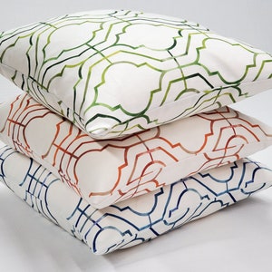 May include: Three decorative throw pillows with a white background and geometric patterns in shades of green, orange, and blue.