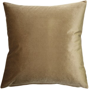 May include: A square, solid-colored pillow in a warm, muted gold hue. The pillow has a soft, velvety texture and a subtle sheen, suggesting a plush, comfortable design. The pillow is a neutral color, suitable for various interior design styles.