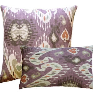 May include: Two decorative throw pillows with an ikat pattern in shades of purple, brown, green, and cream.