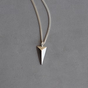 May include: A silver chain necklace with a geometric silver pendant shaped like a triangle.